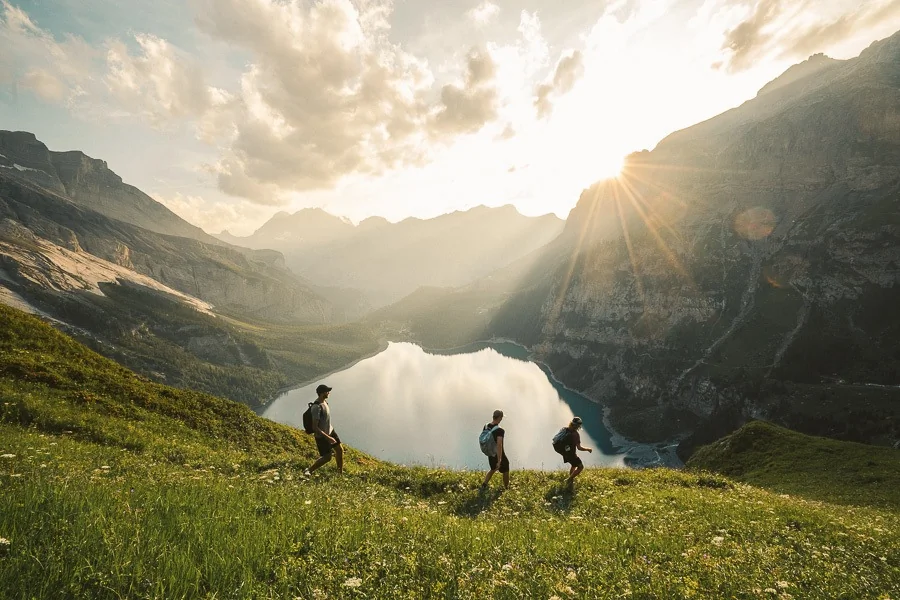 Hikers exploring a steep mountain trail alongside a vibrant blue alpine lake